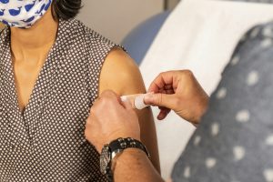 a nurse applies a bandaid to a woman's arm post vaccination